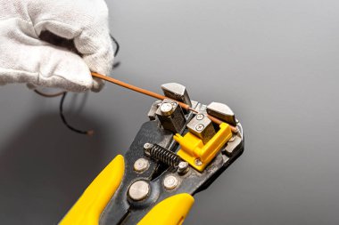 Bir elektrikçi faz kablosunu montaj için otomatik yalıtım striptizcisi kullanır..