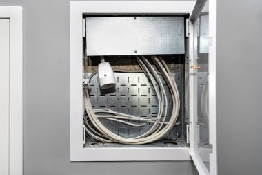 Garajın gri duvarına anten, internet ve elektrik kabloları yerleştirilmiş multimedya kutusunu aç.