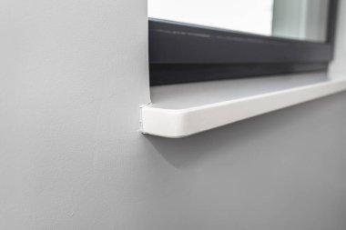 Odanın içine, gri duvara yeni yerleştirilmiş beyaz holdingin pencere pervazı..