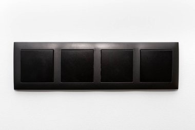 Evin gri duvarında dört düğmeli lamba anahtarı olan siyah çerçeve..