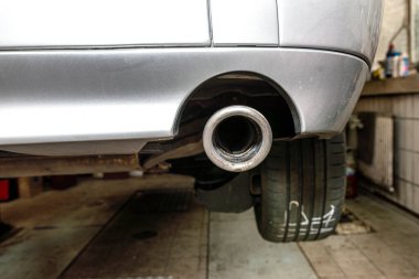 Arabadaki egzoz sistemi, görünür egzoz ucu, araba tamirhanedeki asansörde..