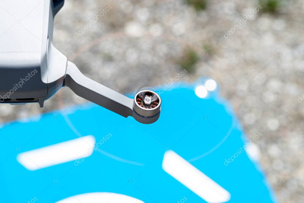 A close-up shot of the drone rotating plastic propellers with brushless motors against the backdrop of a blue landing pad.