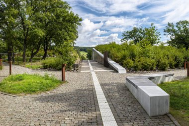 Kayalarla binanın duvarları arasında uzanan kaldırım taşlarından oluşan bir sokak. Ağaçlı bir tarla..