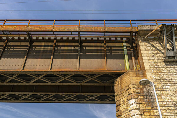 The steel lattice structure of the railway bridge viewed from below against the blue sky.