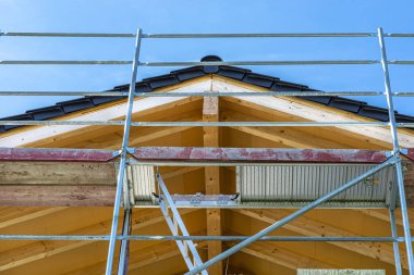 Çatı kirişi aşağıdan çivilenmiş, görünür metal yapı iskelesi ile görünüyor..