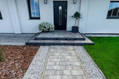 Entrance to the house made of paving slabs, visible pebbles and bark.