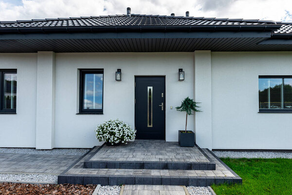 Entrance to the house made of paving slabs, visible pebbles and bark.