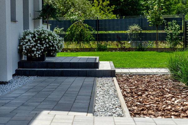 Entrance to the house made of paving slabs, visible pebbles and bark.