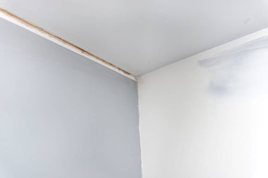 Askılara asılmış alçıpandan yapılmış tavanın altındaki duvardaki çatlak..