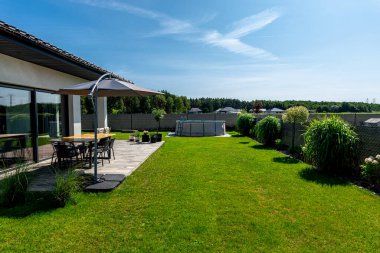 Çapı 3.96 metre olan büyük bir genişleme havuzu bahçedeki çimlerin üzerinde plastik bir yaprak üzerine yerleştirilir..