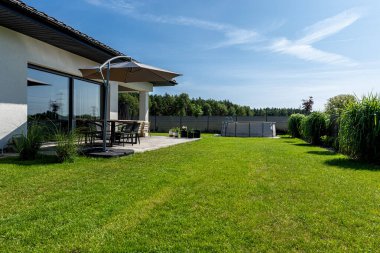 Çapı 3.96 metre olan büyük bir genişleme havuzu bahçedeki çimlerin üzerinde plastik bir yaprak üzerine yerleştirilir..