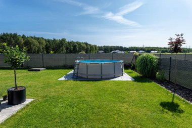 Çapı 3.96 metre olan büyük bir genişleme havuzu bahçedeki çimlerin üzerinde plastik bir yaprak üzerine yerleştirilir..