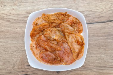 Çiğ tavuk göğsü filetoları baharatlarla marine edilir, pişirmeye hazırlanır.