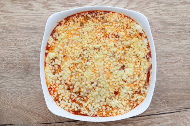 Ahşap bir masada, beyaz bir fırına dayanıklı lazanya pişirme.