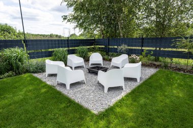 Çağdaş oturma yerleri ve çakıl üzerinde merkezi ateş çukuru olan bahçe avlusu.