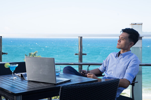 Молодой бизнесмен работает на ноутбуке в кафе-магазине
