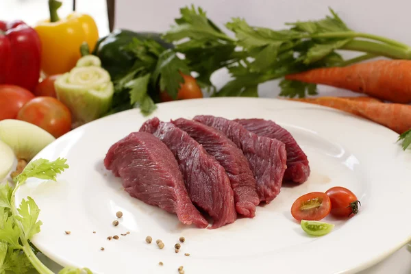 Skiva rå strutskött med grönsaker Stockfoto