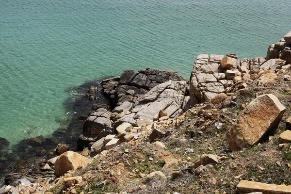 Rochas na praia com céu azul e montanha, a costa rochosa — Fotografia de Stock