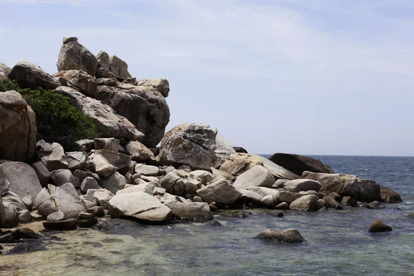 Mavi gökyüzü ve dağ, kayalık sahil ile plajda kayalar