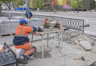 Worker cuts paving tiles on the machine tool