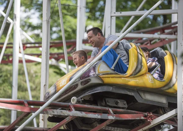 Children with father ride the ride "roller coaster" — Stock Photo, Image
