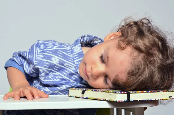 Niño aprendiendo a escribir y leer. Pequeño niño que se divierte preparándose para la escuela, pero demasiado cansado después de una lección, se fue a dormir —  Fotos de Stock