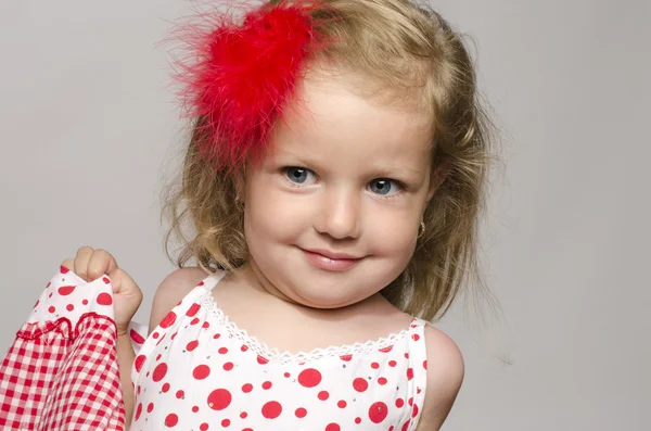 Little adorable blonde girl with a red flower in her hair smiling and having fun, toddler playing — Stock Photo, Image