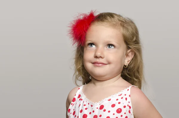 Aranyos szőke kislány egy piros virág a hajában, mosolyog, és a szórakozás, totyogó játszik — Stock Fotó