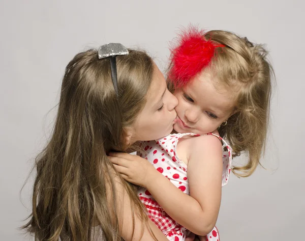 Fiatal lány, gazdaságban a karjában, csók és birtoklás móka-val a kis húga. a gyerekek játszani és nevetni — Stock Fotó