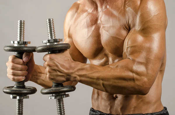 Strong bodybuilder man with perfect abs, shoulders,biceps, triceps and chest, personal fitness trainer training with heavy dumbbells — Stock Photo, Image