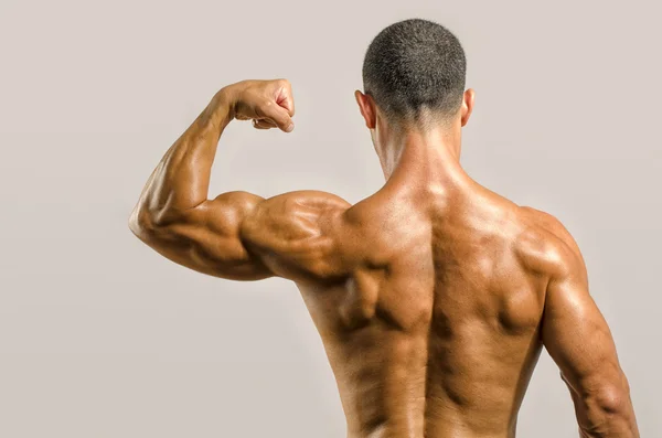 Bodybuilder showing his back and biceps muscles isolated on a white background, personal fitness trainer — Stock Photo, Image