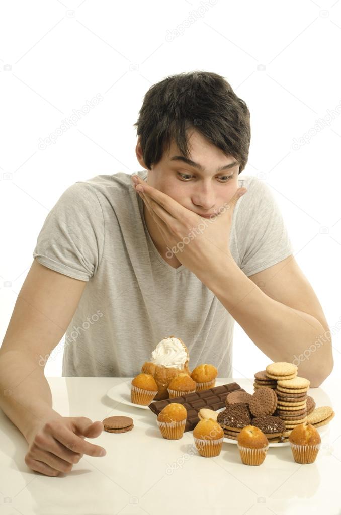 Man in love with sweets, candies,chocolate and sugar but trying to withhold. Forbidden sweets for a healthy longer life