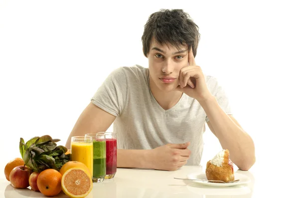 Mann hat die Wahl zwischen Obst, Smoothie, Salat und gesunder Bio-Kost gegen Süßigkeiten, Zucker, viele Bonbons — Stockfoto