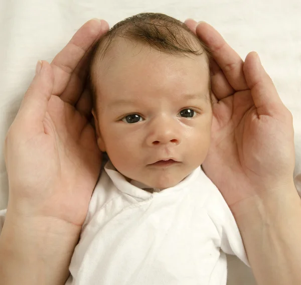 Beautiful innocent newborn looking at his father. Adorable little boy relaxing in white sheets after a bath, father's hands holding his newborn with love — Stock Photo, Image