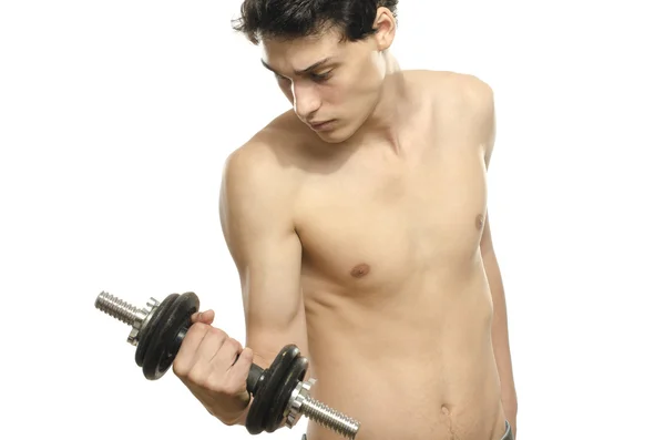 Der schlanke Mann trainiert seinen Bizepsmuskel. schöner Teenager, der eine Hantel hebt. Magersucht junger Mann trainiert, um stärker zu werden — Stockfoto