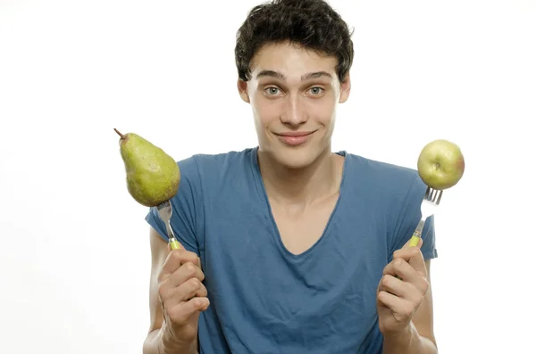 Ein hagerer junger Mann isst eine gesunde, saftige Birne und einen Apfel. Grünes Essen für ein gesundes Leben und eine perfekte Ernährung — Stockfoto