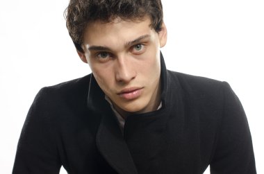 Güzel genç bir adam portresi moda poz bir siyah uzun ceket içinde giyinmiş