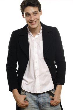 Portrait of a beautiful young man dressed in a black long coat and jeans, posing fashion