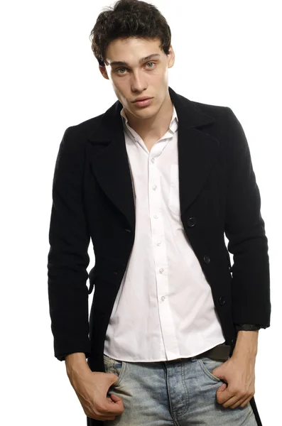 Portrait of a beautiful young man dressed in a black long coat and jeans, posing fashion — Stock Photo, Image