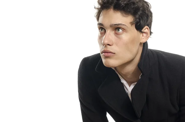 Retrato de un hermoso joven vestido con un abrigo largo negro, posando de moda — Foto de Stock