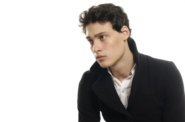 Retrato de un hermoso joven vestido con un abrigo largo negro, posando de moda —  Fotos de Stock