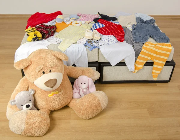 Bear toy on a bed with different colorful new born clothes.Colorful wardrobe of newborn,kids, babies full of all clothes, shoes,accessories and toys — Stock Photo, Image