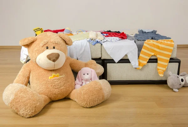 熊玩具放在不同颜色的新生儿衣服的床上。五颜六色的新生儿、儿童、满屋子的婴儿、鞋子、配件和玩具 — 图库照片