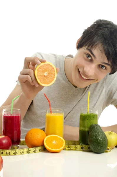 Feliz hombre preparando un batido orgánico naranja. Hermoso hombre exprimiendo una mitad de una naranja y teniendo una comida saludable con zumos de manzana y naranja —  Fotos de Stock