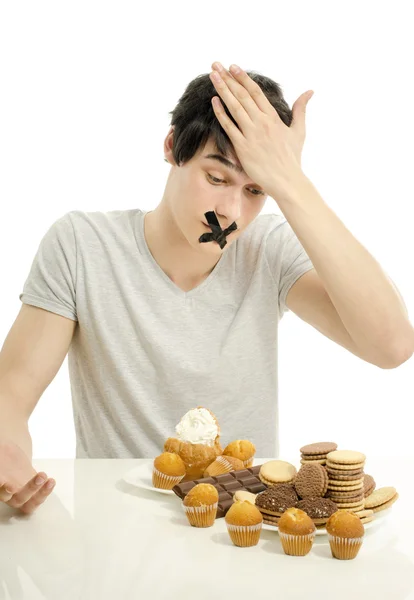 Homme amoureux de bonbons, bonbons, chocolat et sucre mais essayant de retenir. Bonbons interdits pour une vie plus longue en bonne santé — Photo