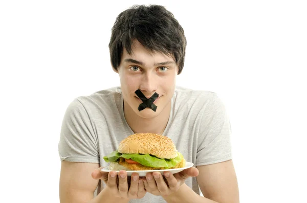 Homme avec une bande noire sur la bouche incapable de manger un gros hamburger, jeune homme suivre un régime et avoir un moment difficile avec la restauration rapide — Photo