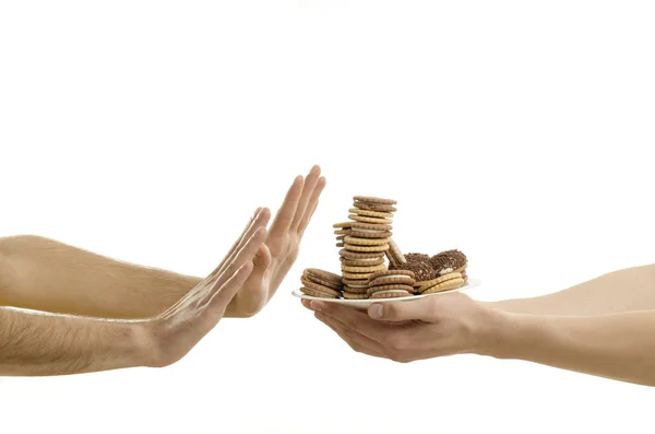 Man's hand offering chocolate, cupcakes, biscuits, cookies, muffins and oher hands receiving. Lots of sugar in a plate — Stock Photo, Image