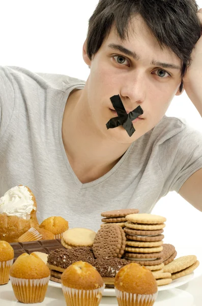 Hombre enamorado de dulces, caramelos, chocolate y azúcar pero tratando de retener. Dulces prohibidos para una vida más larga y saludable — Foto de Stock