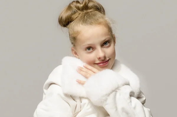 Κοπέλα φορώντας ένα λευκό μακρύ παλτό και ψάχνει ήθελε χιόνι λευκό, όμορφο παιδί προθερμαίνεται επάνω για το χειμώνα — Φωτογραφία Αρχείου