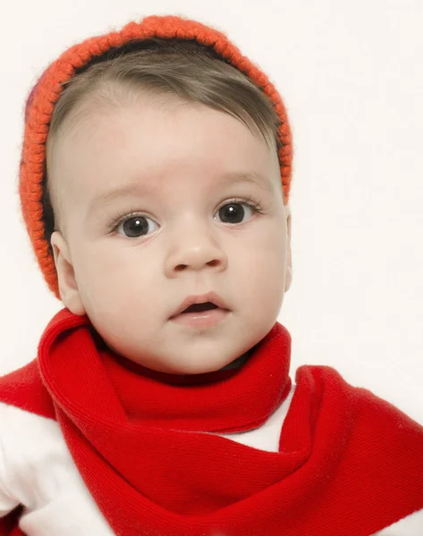 Innocent baby wearing a red hat and a muffler and looking adorable. Small kid dressed for winter — Stock Photo, Image